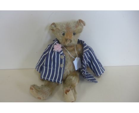 An early 1900's Steiff bear, with boot button eyes, 25cm tall, split to left ear, no button, holes and tear to the back and f