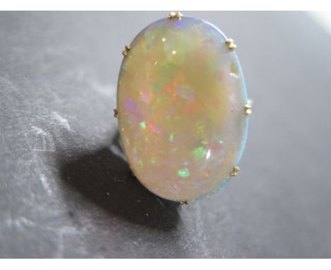 An opal set dress ring, yellow D profile shank and shoulders set to a single, oval, cabochon cut opal in galleried, claw sett