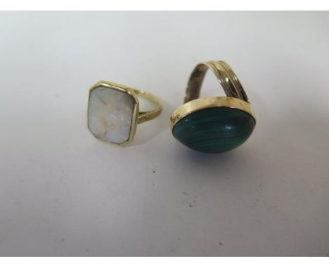 A yellow metal dress ring, grooved, offset shank to an oval cabochon of malachite, 19.5mm x 14.8mm, in a plain bezel setting,