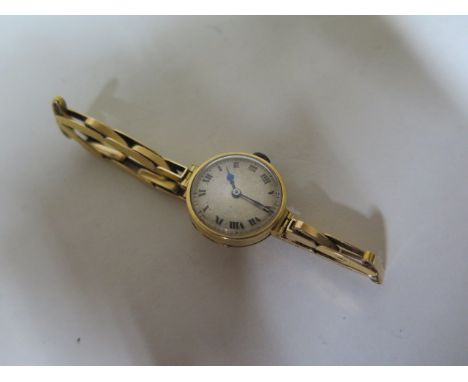 An 18ct ladies manual wind watch on a 15ct sprung strap, total weight approx 14 grams, running 