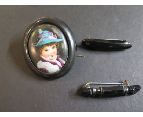 A jet oval brooch with porcelain plaque centre containing transfer printed and coloured portrait of woman and two other jet b