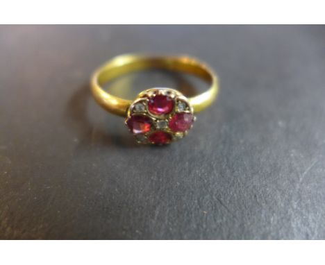 A 9ct gold ruby and diamond ring set with four rubies around a small central diamond chip and a further four diamond chips be