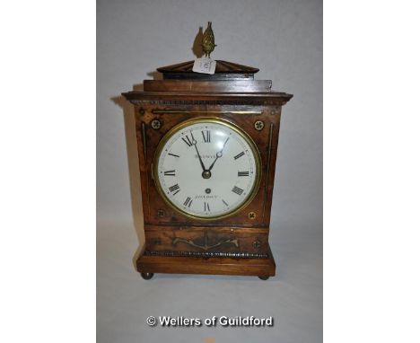 An early 19th Century mahogany cased mantel clock with pineapple finial and brass inlay, the white enamel dial with Roman num