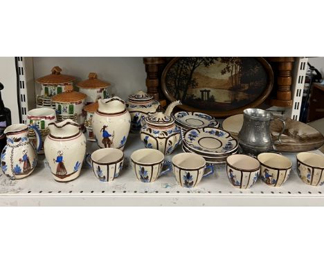 A Quimper part tea service together with a pottery plate painted with a landscape scene, signed M Prevot, tray and storage ja