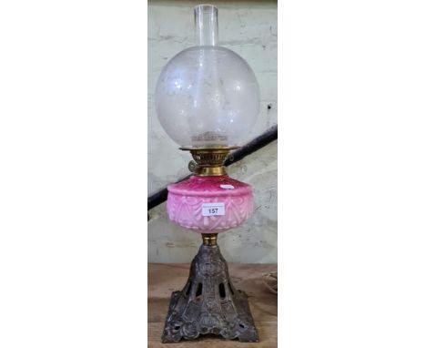 A pink glass and brass oil lamp with cast metal base. There are two or three small bubbles in the pink glass appx 3-4mm long,