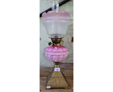 A pink glass and brass oil lamp with cast metal base. Minor scratching to gilding where base joins lamp. There is a hairline 
