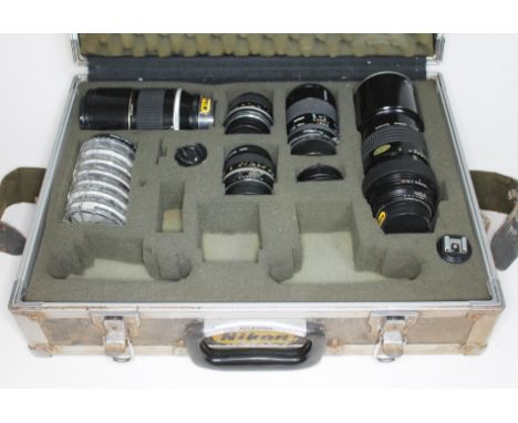 A flight case containing four Nikon Nikkor; 300mm 1:45, 85mm 1:2, 35mm 1:2.8 &amp; ED 180mm 1:2.8, together with a Tamron len