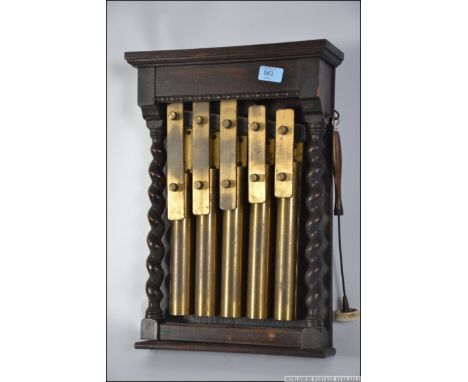 A vintage wall hanging xylophone, having an oak surround with barley twist column supports both sides of the five brass keys