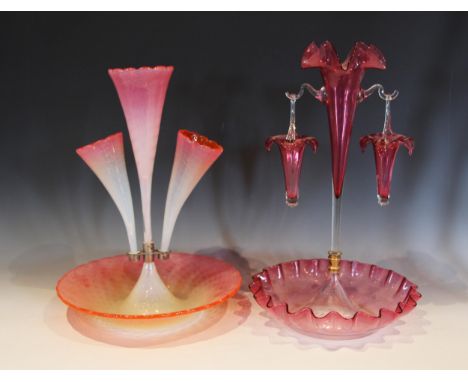 A cranberry glass epergne, with a central trumpet supporting two hanging baskets, each rim modelled as a lily flower, 44.5cm 