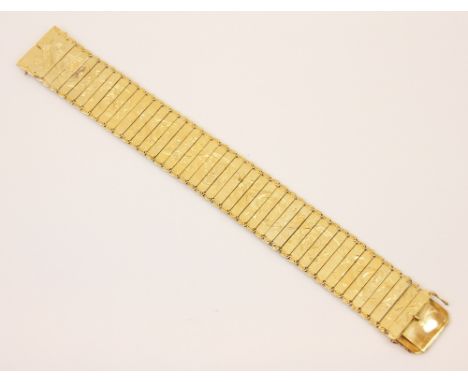 A yellow metal flat link bracelet, the bracelet with engraved floral scrolling decoration and each panel with scroll terminal
