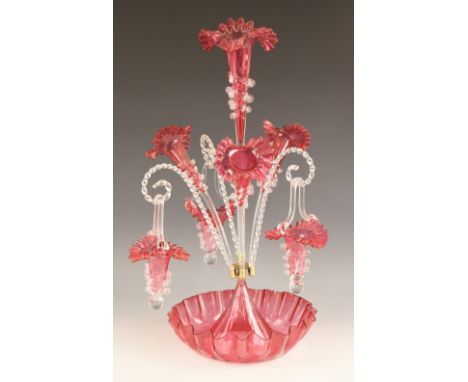 A cranberry glass epergne of typical form, with central trumpet over three lower trumpets, and three canes supporting hanging