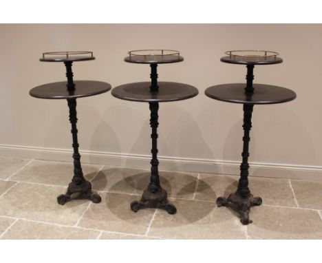 A trio of Victorian cast iron and hardwood two tier pub or bar tables, the two circular graduated tiers upon a fluted column 