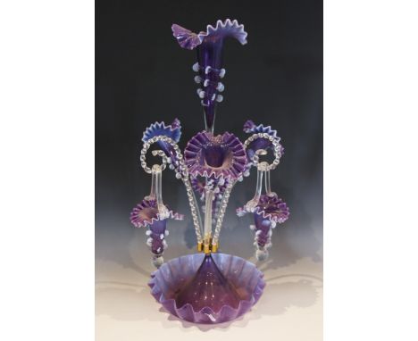 A purple glass epergne of typical form, with central trumpet over three lower trumpets, and three canes supporting hanging ba