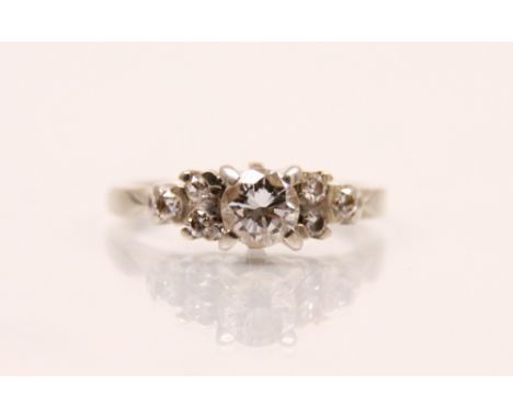 A late 20th century diamond ring, the central round cut diamond in four claw setting, with three smaller round cut diamonds t