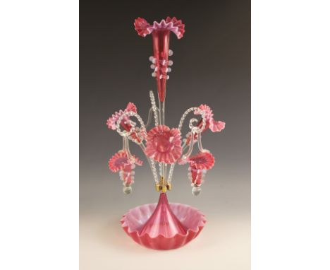 A cranberry glass epergne of typical form, with central trumpet over three lower trumpets, and three canes supporting hanging