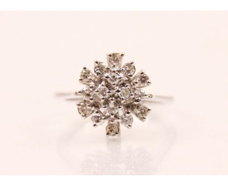 A late 20th century diamond and white metal cluster ring, the head of the ring designed as sixteen round cut diamonds within 