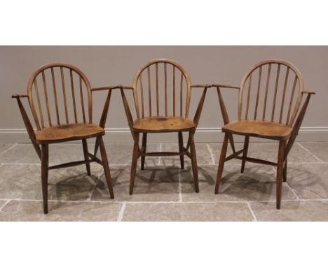 A trio of elm and beech Ercol type elbow chairs, mid 20th century, each with a hoop back, out swept arms and figured elm seat