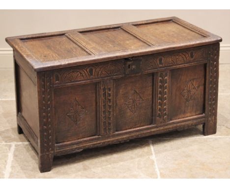 A carved oak coffer, late 17th/early 18th century, the pin and hook hinged top with three inverted panels, over a lunette and