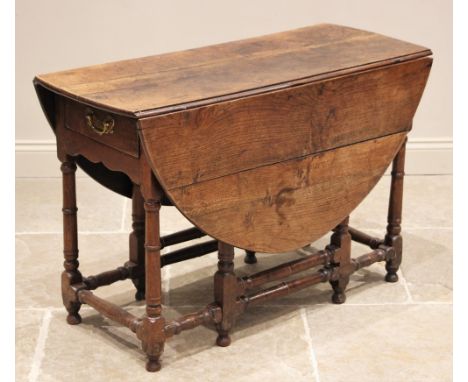 A late 17th century oak gate leg table, the oval plank top above a single frieze drawer, upon ring turned and block supports,