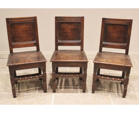 A trio of oak panel back stools/chairs, early 18th century, each with a recessed panel back over a board seat, upon bobbin an