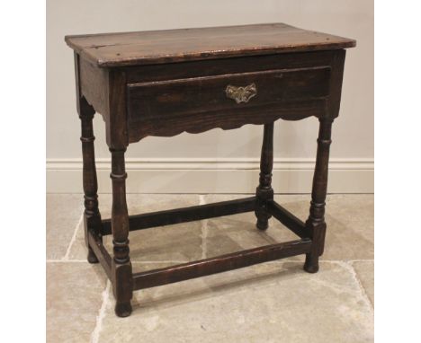An 18th century oak side table, of cottage proportions, the twin plank top over a single frieze drawer and shaped apron, upon