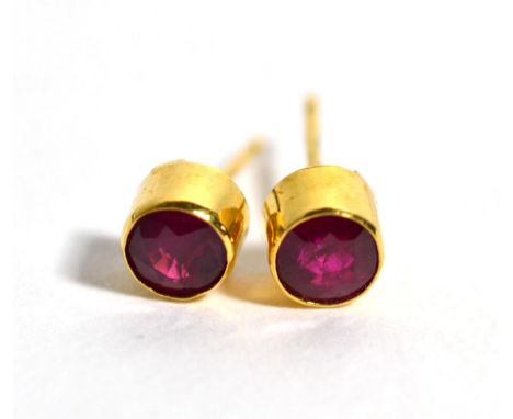 A pair of 18 carat gold ruby stud earrings, in rubbed over settings, 5.4mm in diameter, with post fittings  The earrings are 