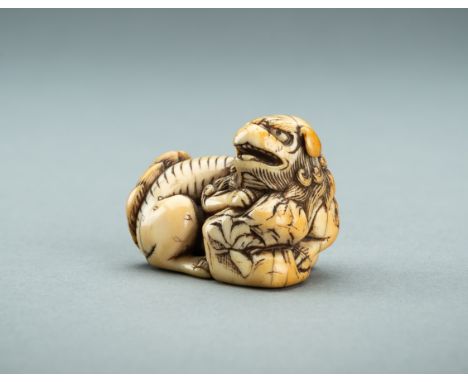 AN IVORY NETSUKE OF A SHISHI WITH BAG, 18th CENTURYJapan, 18th century, Edo period (1615-1868)Carved seated, the flaming tail