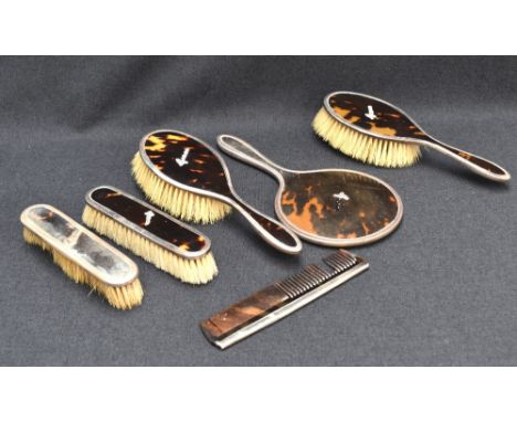 A George V silver and tortoiseshell six piece dressing set, comprising a hand mirror, two clothes brushes, two hair brushes a