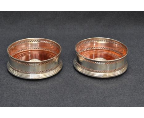 A pair of Queen Elizabeth II silver and mahogany wine coasters, of traditional design with bands of pierced decoration over t