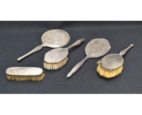 A George VI silver mounted three-piece dressing table set, comprising hand mirror, hair brush and clothes brush, each engine-
