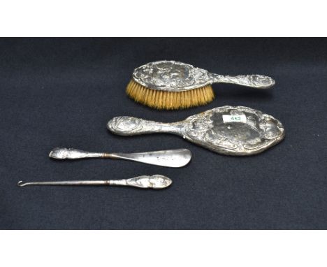 An Edwardian silver-mounted four-piece 'Dream of Love' dressing table set, comprising a hand mirror, hair brush, shoe horn an