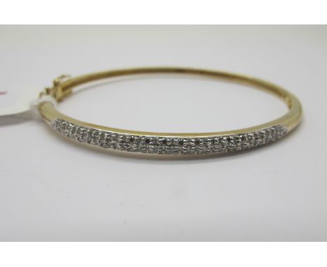 A Modern 9ct Gold Diamond Set Bangle, millegrain set to the front with brilliant cut stones, hinged to snap clasp (internal d