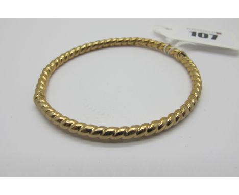 A Modern Bangle, of uniform twisted design, hinged to snap clasp, stamped "375" (internal diameter 5.8cm) (5grams). 