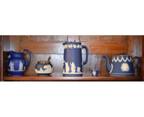 Two Wedgwood dark blue jasperware jugs, an Adams dark blue jasperware teapot, a similar sugar basin and a miniature Wedgwood 