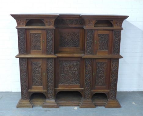 An oak carved court cupboard, the projecting breakfront cornice with two arch recesses over two panelled doors with a central