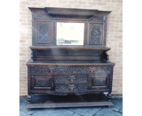 A LARGE HIGHLY CARVED OAK MIRROR BACK SIDEBOARD  the base with pair of drawers with lion mask handles above further pair of d