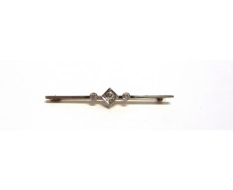 AN EARLY 20TH CENTURY GOLD AND DIAMOND THREE STONE BAR BROOCH the central cushion-shaped old-cut stone approx. 0.25cts, grain