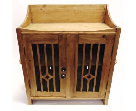 A STRIPPED PINE WALL CUPBOARD  the doors with pierced mesh grille panels and candle shelf to each side, 76cm wide 73cm high