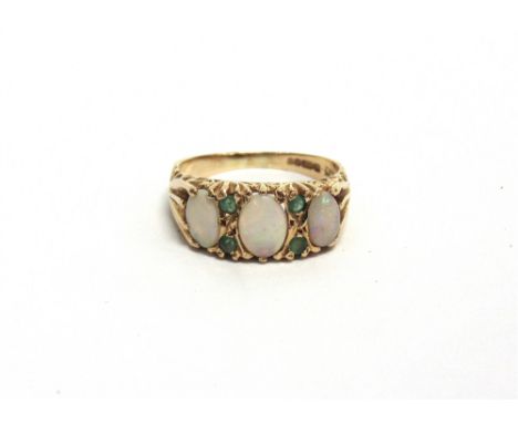 A 14CT GOLD, OPAL AND EMERALD DRESS RING the three graduated oval white opal cabochons spaced by pairs of small round emerald