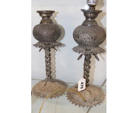 A PAIR OF INDIAN SILVER COLOURED METAL OIL LAMP BASES WITH ETCHED FONTS AND ENTWINED COBRA BASES