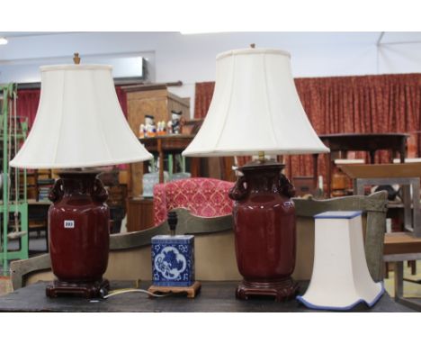 A PAIR OF SANG DE BOEUF TABLE LAMPS WITH SHADES AND A BLUE AND WHITE TABLE LAMP