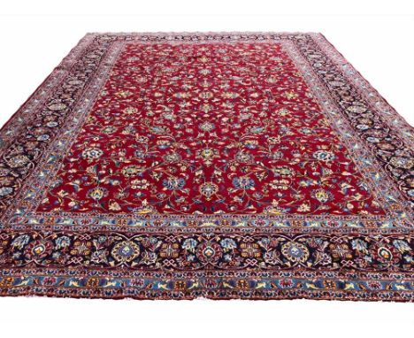 FINE PERSIAN KASHAN CARPET, 412cm x 310cm, all over palmette and vine design on a ruby field within corresponding bands and b