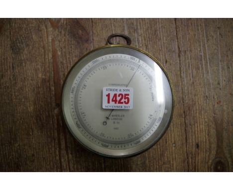 A brass cased aneroid barometer, the silvered dial inscribed 'T Wheeler, London, 1937', 12cm diameter. 