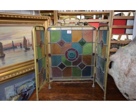 A brass framed, stained and leaded glass triptych firescreen.