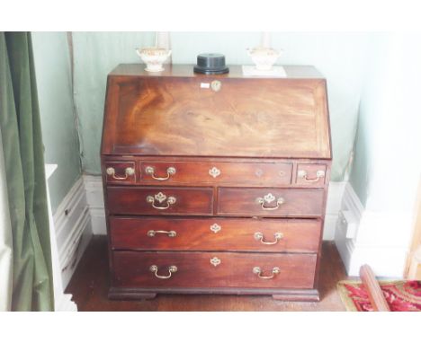 A GEORGE III MAHOGANY BUREAU the fall front opening to an interior fitted with a central cupboard flanked by architectural pi