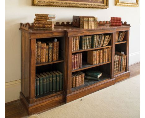 A LATE REGENCY ROSEWOOD BREAKFRONT OPEN BOOKCASE with a castellated back and adjustable shelves divided by architectural colu
