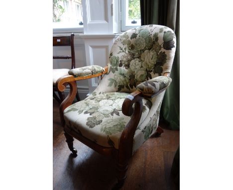 AN EARLY VICTORIAN MAHOGANY SPOONBACK ARMCHAIR upholstered in floral material, on ring-turned tapering legs and castors, 26" 