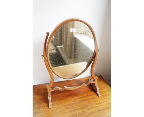 A SHERATON STYLE MAHOGANY DRESSING MIRROR the oval plate on a curved frame with splay bracket feet, 17" wide 