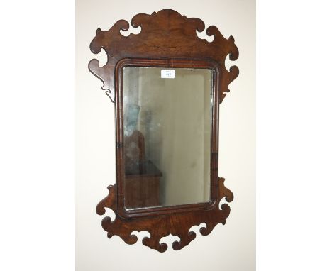 A CHIPPENDALE STYLE WALNUT WALL MIRROR the rectangular plate within a fretwork surround, 27" wide 