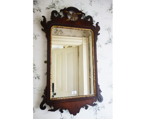 A CHIPPENDALE STYLE MAHOGANY WALL MIRROR the rectangular plate within a fretwork surround surmounted by a pierced giltwood ho